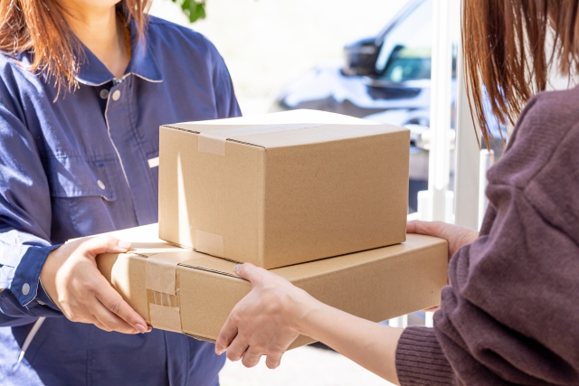 配達員から荷物を受け取る女性
